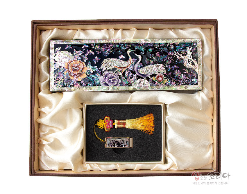 [텍스트: 샵오브코리아 대한민국의 품격까지 전합니다] 흑색 옻칠 바탕 위 자개 상감 송학·모란·소나무 문양 필함과 노랑 술 매듭 장식 자개 USB 세트 구성