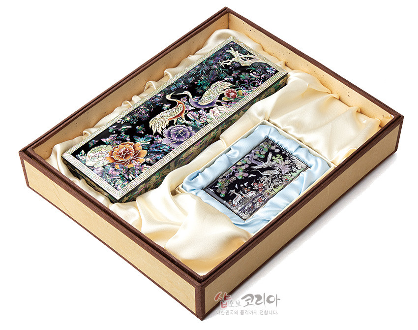 [텍스트: 샵오브코리아 대한민국의 품격까지 전합니다.] 흑색 옻칠 바탕 위 자개 상감으로 송학과 모란, 소나무 문양을 섬세하게 표현한 필함·명함케이스 세트 구성