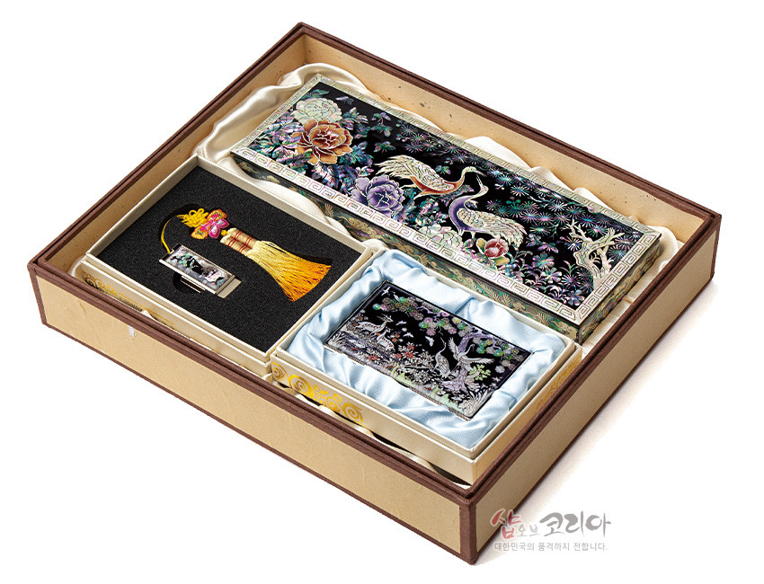 [텍스트: 샵오브코리아 대한민국의 품격까지 전합니다.] 흑색 옻칠 바탕 위 자개 상감 기법으로 송학과 모란, 소나무 문양을 넣은 필함·명함케이스·USB 3종 세트 이미지