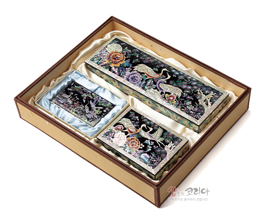 [텍스트: 샵오브코리아 대한민국의 품격까지 전합니다.] 흑색 옻칠 바탕 위 자개 상감 기법으로 송학과 모란, 소나무 문양을 표현한 필함·명함함·명함케이스 세트 이미지