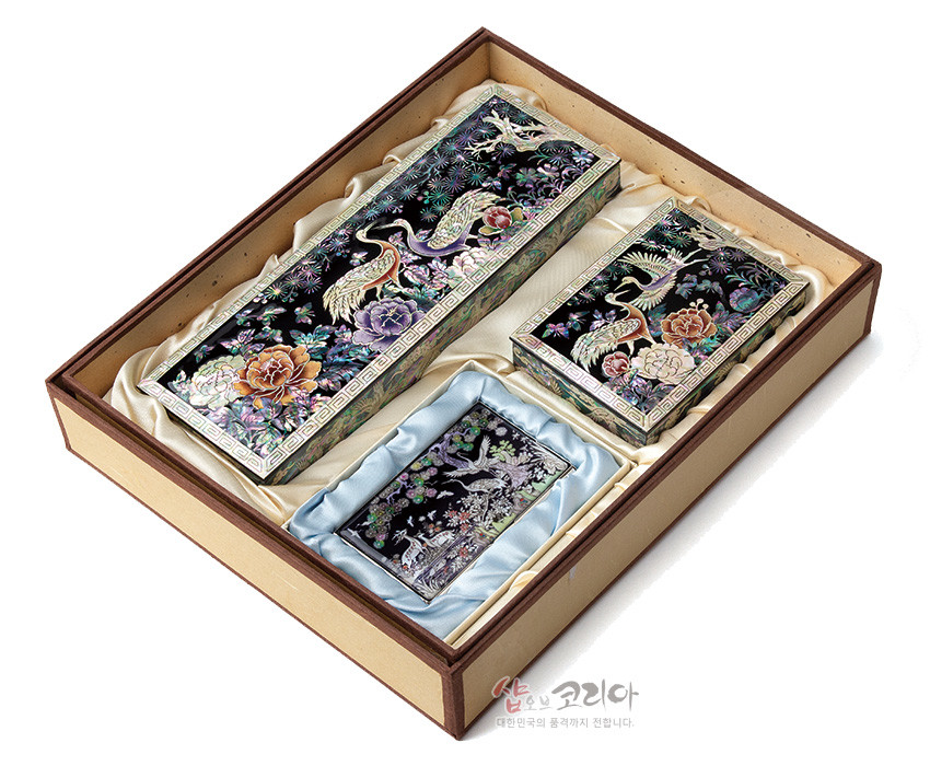 [텍스트: 샵오브코리아 대한민국의 품격까지 전합니다.] 흑색 옻칠 바탕 위 자개 상감 기법으로 송학과 모란, 소나무 문양을 화려하게 표현한 필함·명함함·명함케이스 세트 이미지