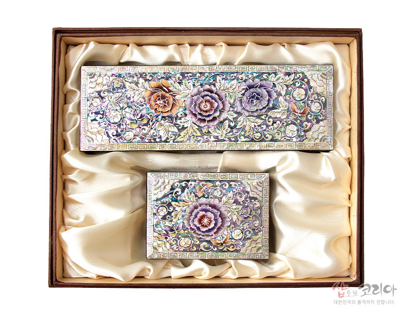 [텍스트: 샵오브코리아 대한민국의 품격까지 전합니다.] 자개 상감 기법의 목단·나비 문양 나전칠기 필함·명함함 세트, 오색 광택과 금색 잎사귀 장식, 아이보리색 비단 내피 대비 이미지 설명
