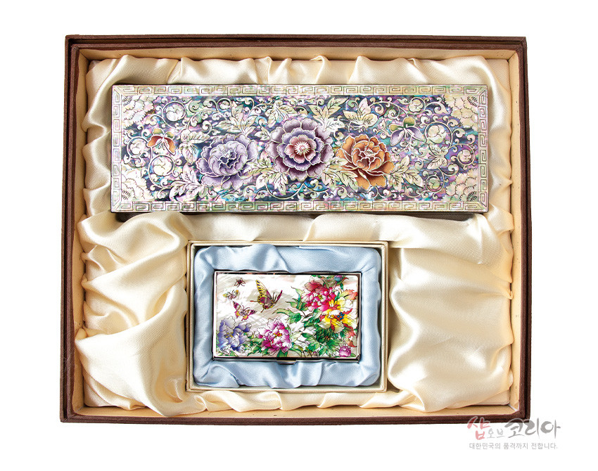 [텍스트: 샵오브코리아 대한민국의 품격까지 전합니다.] 자개 상감 기법의 나전칠기 필함과 명함케이스 세트, 모란·나비 문양과 오방색 계열 꽃문양이 실크 패브릭 내장 박스에 배치된 구성