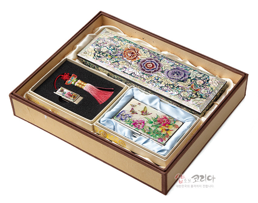[텍스트: 샵오브코리아 대한민국의 품격까지 전합니다.] 자개 상감 기법의 모란·나비 문양 필함과 명함케이스, 홍색 술 장식 USB가 조화를 이루는 다채로운 나전칠기 세트 구성