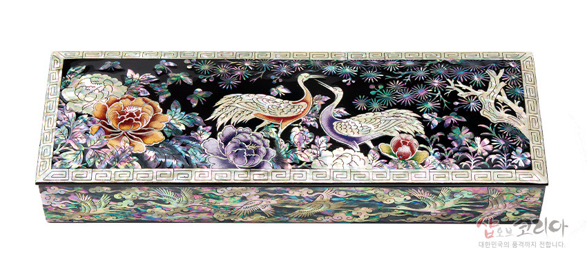 [텍스트: 샵오브코리아 대한민국의 품격까지 전합니다.] 흑색 옻칠 바탕 위 자개 상감 기법, 송학과 모란, 소나무 문양을 다채로운 색감으로 표현한 직사각형 필함 디자인