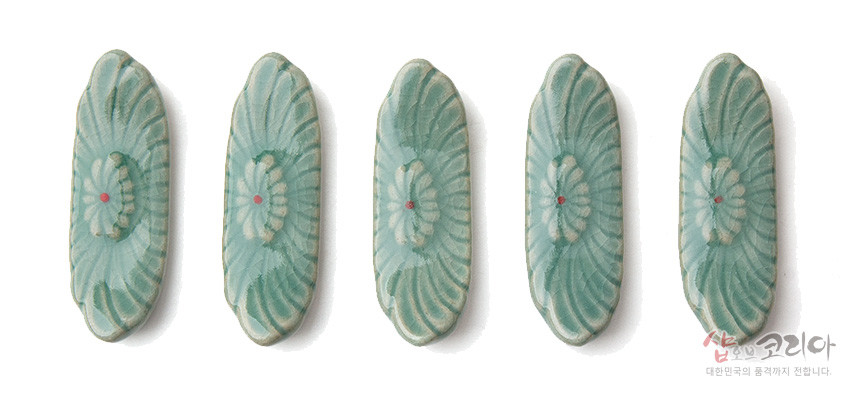 [텍스트: 샵오브코리아 대한민국의 품격까지 전합니다.] 청자 재질에 연녹색 유약을 입힌 수저받침 5종, 음각 꽃무늬와 중앙 붉은 점 포인트가 조화를 이루는 디자인