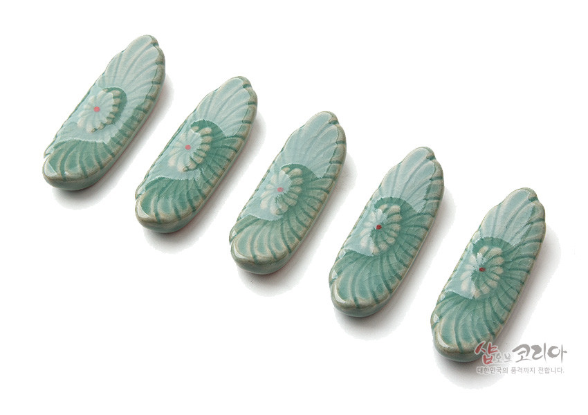 [텍스트: 샵오브코리아 대한민국의 품격까지 전합니다.] 옅은 비취색 유약을 입힌 청자 수저받침, 음각 꽃무늬와 분홍색·붉은 점 포인트가 조화를 이루는 5종 세트 이미지