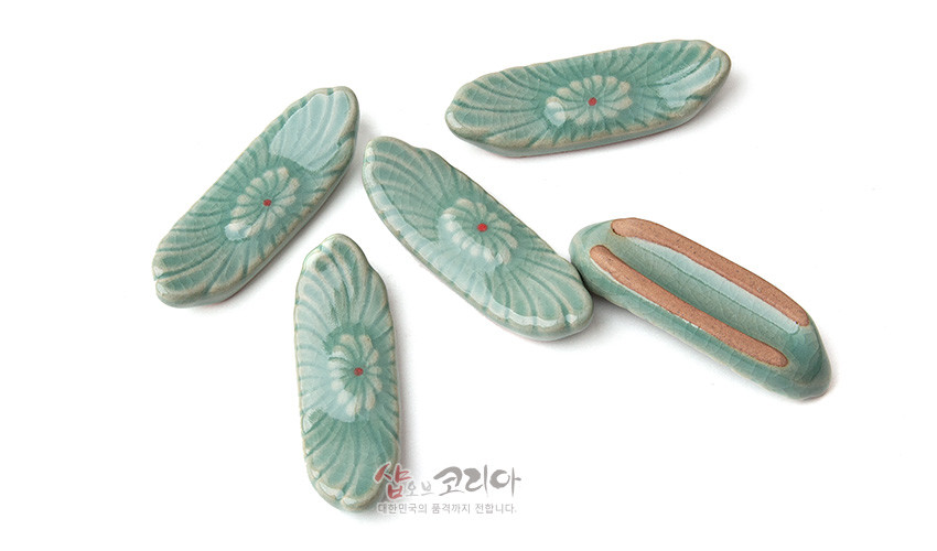 [텍스트: 샾오브코리아 대한민국의 품격까지 전합니다.] 연녹색 비취빛 유약을 입힌 청자 수저받침, 음각 꽃무늬와 붉은 점 장식, 바닥 무유 처리된 5종 구성 이미지 설명