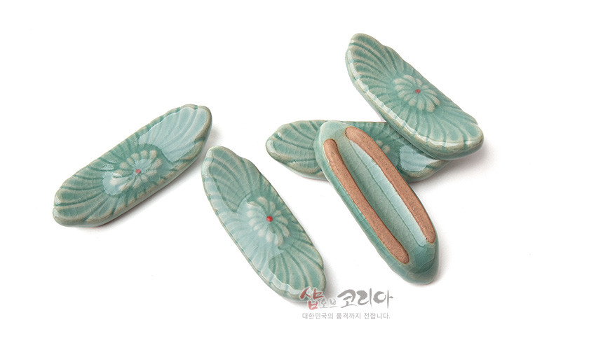 [텍스트: 샵오브코리아 대한민국의 품격까지 전합니다.] 연녹색 유약의 청자 수저받침, 음각 꽃무늬와 붉은 점 장식이 있는 5종 세트 이미지