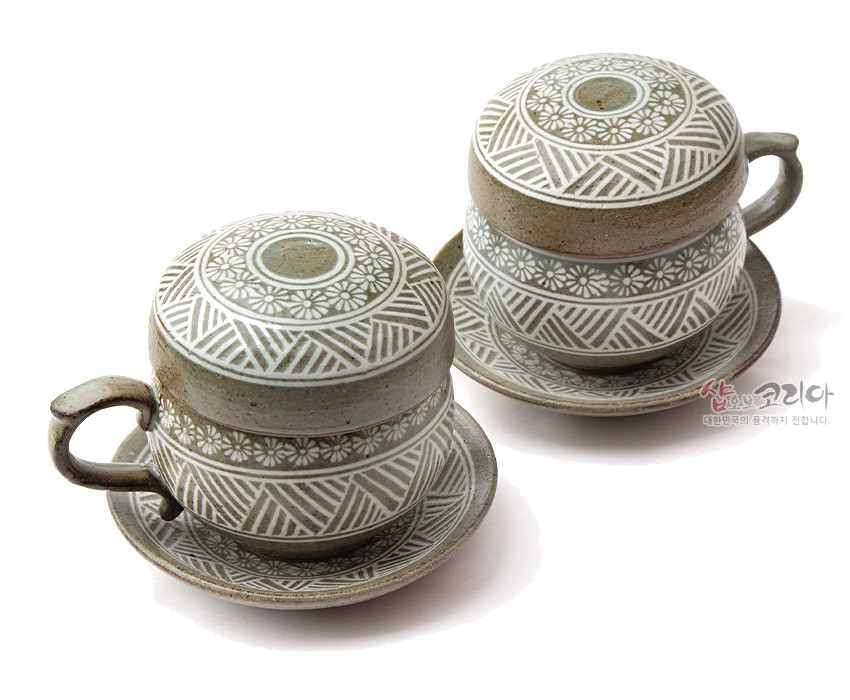 [텍스트: 샵오브코리아 대한민국의 품격까지 전합니다.] 분청사기 재질에 백색 상감 기법으로 국화문과 기하학 문양을 두른 회갈색 2인용 뚜껑잔과 받침 접시 세트 이미지 설명