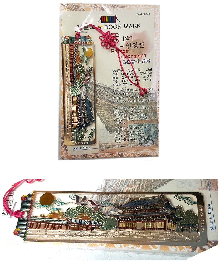 [텍스트: BOOK MARK, 인정전, Injeongjeon, Palace, Made in Korea] 금장 금속 재질 위에 창덕궁 인정전 전경과 산수, 구름, 해와 학 문양을 컬러 에나멜로 섬세하게 채색하고 분홍 전통 매듭 끈으로 장식한 직사각형 책갈피 디자인