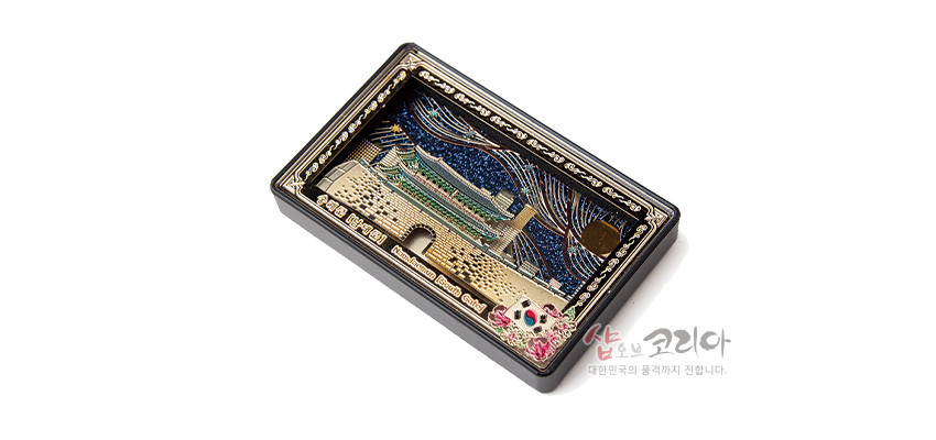 [텍스트: Sungnyemun Gate Namdaemun Seoul Korea 1398] 금속 재질 직사각 프레임에 입체 부조 기법으로 표현된 숭례문과 성곽, 남색 밤하늘과 유선형 문양, 하단 태극과 꽃 장식의 다채로운 색감 대비 이미지