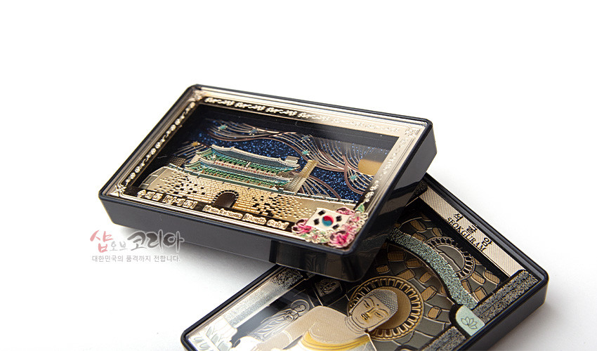 [텍스트: 숭례문, 숭례문 NAMDAEMUN GATE] 밤하늘 배경 위 금속 재질 숭례문 입체 표현, 남색·금색 대비와 태극 문양·꽃 장식 포인트, 반짝이는 금속 질감과 세밀한 선각 기법 특징의 마그넷형 소품 이미지 설명