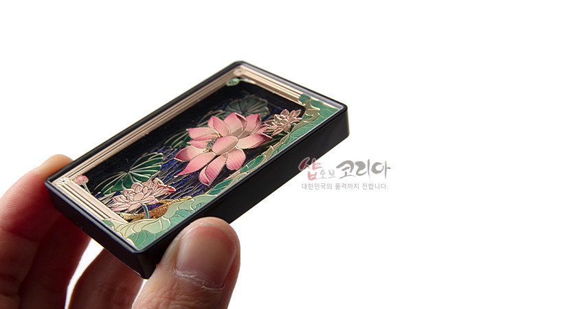 [텍스트: 샵오브코리아, 대한민국의 품격까지 전합니다.] 금속 바탕 위 입체 양각된 분홍 연꽃과 연잎 문양, 청록 수면과 검은 배경의 색채 대비가 돋보이는 직사각형 마그넷 디자인