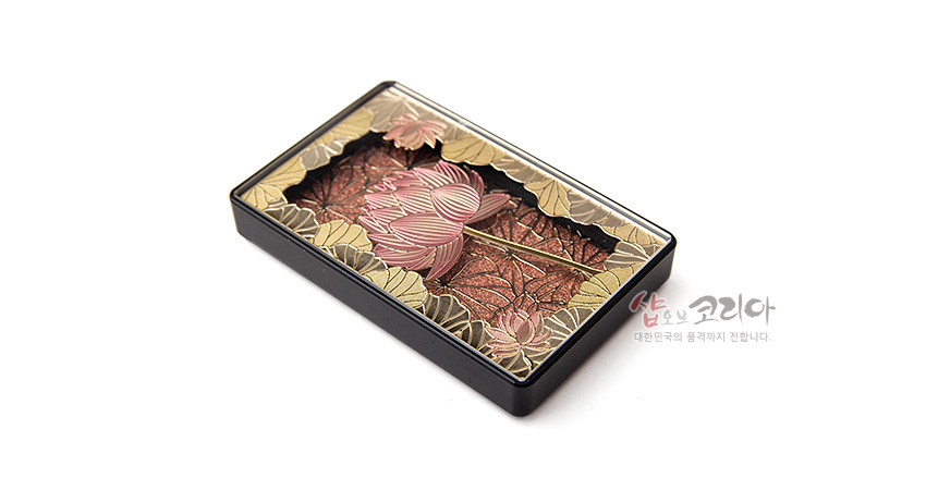 [텍스트: 샵오브코리아 대한민국의 품격까지 전합니다.] 금속 재질 직사각형 마그넷 위에 양각 기법으로 표현된 분홍색 연꽃과 황금색 연잎, 적갈색 배경의 조화로운 입체 문양 장식