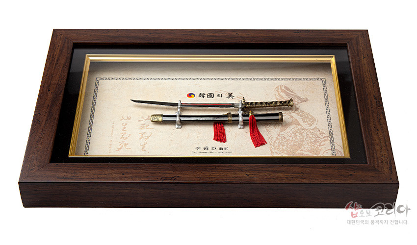[텍스트: 韓國의 美, 李舜臣 장검] 짙은 갈색 나무 액자 속 금속 장검과 칼집, 붉은 술 장식, 전통 무늬 배경지가 조화된 입체 장식 액자형 제품