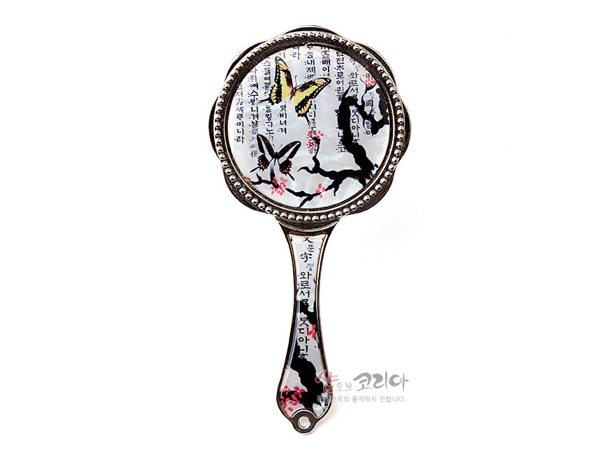 [텍스트: 소망을 이루는 거울 / 쇼핑몰 이름 일부] 자개 느낌의 광택 위에 매화 가지와 나비, 세로 한글 서체가 어우러진 금속 테두리 손잡이 거울 디자인