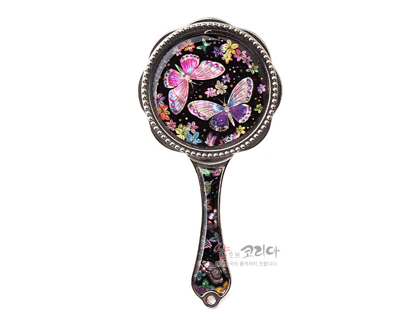 [텍스트: 샵오브코리아 한국의 품격까지 전합니다.] 흑색 바탕 위 자개 상감 기법으로 화려한 나비와 꽃 문양을 표현하고 금속 테두리와 손잡이 장식을 더한 손잡이 거울 모습