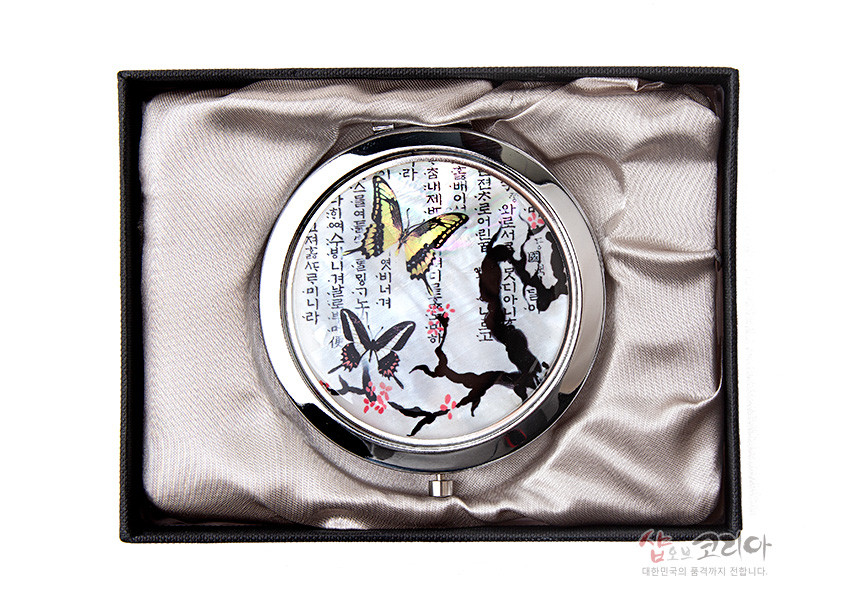 [텍스트: …너를 사랑하나니라] 자개 바탕 위에 매화 가지와 꽃, 노랑·회색 나비 문양을 채색하고 한글 서체를 더한 원형 금속 손거울 디자인