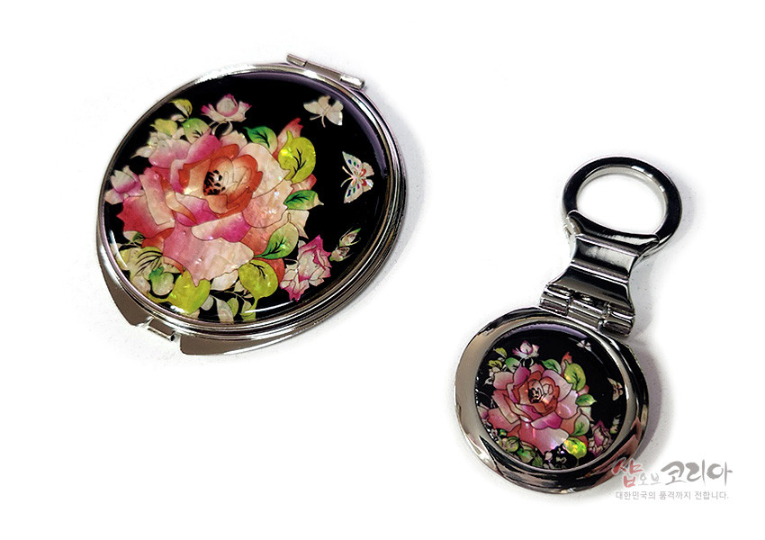 [텍스트: 샵오브코리아 대한민국의 품격까지 전합니다.] 흑색 바탕 위 자개 상감으로 장미와 나비를 섬세하게 표현한 금속 원형 손거울과 키링형 손거울 2종 구성 이미지