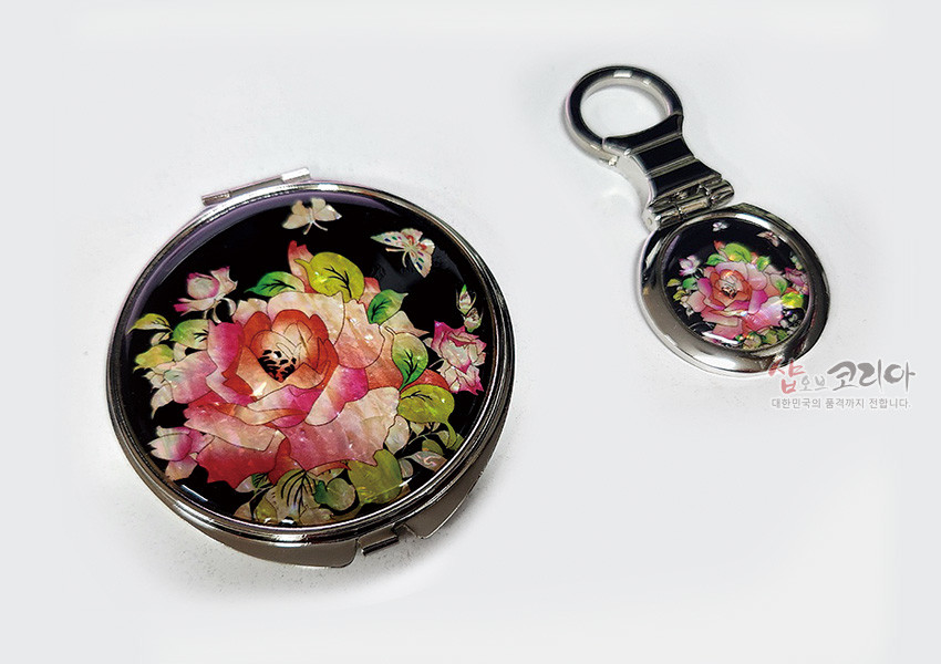 [텍스트: 샾오브코리아 대한민국의 혼과 정까지 전달합니다.] 흑색 바탕 위 다채로운 장미와 나비 문양 자개 상감이 돋보이는 금속 원형 손거울 2종 세트 이미지 설명