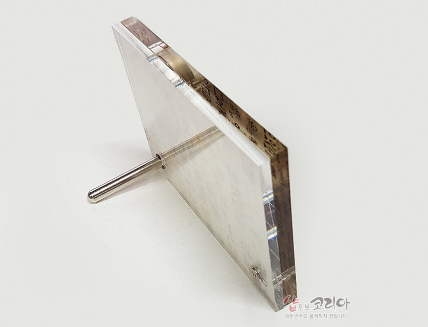 [텍스트: 샵오브코리아 대한민국의 문화까지 전합니다.] 투명 아크릴과 메탈 스탠드 조합, 측면에 한지 질감과 훈민정음 문양이 비치도록 디자인한 직사각 탁상시계 측면 이미지 설명