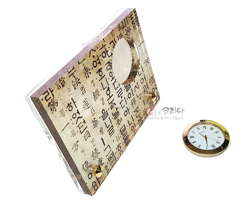 [텍스트: 샵오브코리아] 한지 질감 배경 위에 훈민정음 서체 문양을 인쇄하고 투명 아크릴과 금속 프레임 원형 시계를 결합한 직사각 탁상시계 디자인