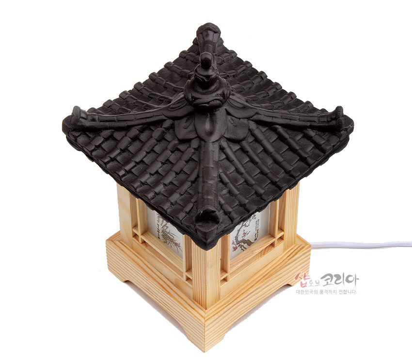 [텍스트: 샵오브코리아 대한민국의 품격까지 전합니다.] 짙은 흑색 기와지붕과 연한 원목 창살, 반투명 한지면에 사군자 채색화 문양이 어우러진 전통 사각 좌등 조명 디자인