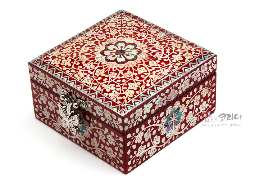 [텍스트: 샵오브코리아 대한민국의 품격까지 전합니다.] 붉은 옻칠 바탕 위 자개 상감으로 당초문과 꽃무늬를 정교하게 표현하고, 은색 금속 잠금장식과 가장자리 기하학 문양 포인트를 준 사각 정보석함 모습