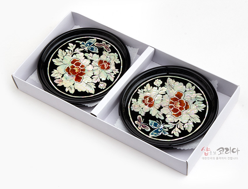 [텍스트: 샵오브코리아 대한민국의 품격까지 전합니다] 흑색 옻칠 바탕 위 자개 상감 기법으로 목단꽃과 나비 문양을 섬세하게 표현한 원형 나전칠기 컵받침 세트 이미지 설명