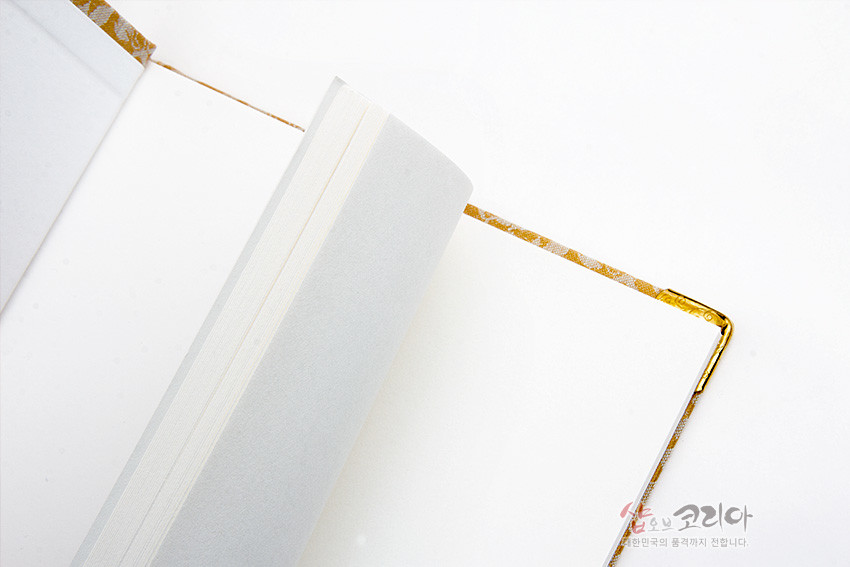 [텍스트: 샵오브코리아] 금색 꽃넝쿨 문양 비단 표지와 금속 모서리 장식, 크림색 속지를 엮은 전통 오침 제본 노트 내부 모습