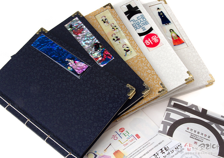 [텍스트: 한복, 훈민정음과 한글] 짙은 남색·금색·아이보리색 비단 표지에 꽃무늬 문양과 금속 모서리 장식, 측면 노끈 제본, 자개 한복 인물 장식이 더해진 전통 오침노트 구성