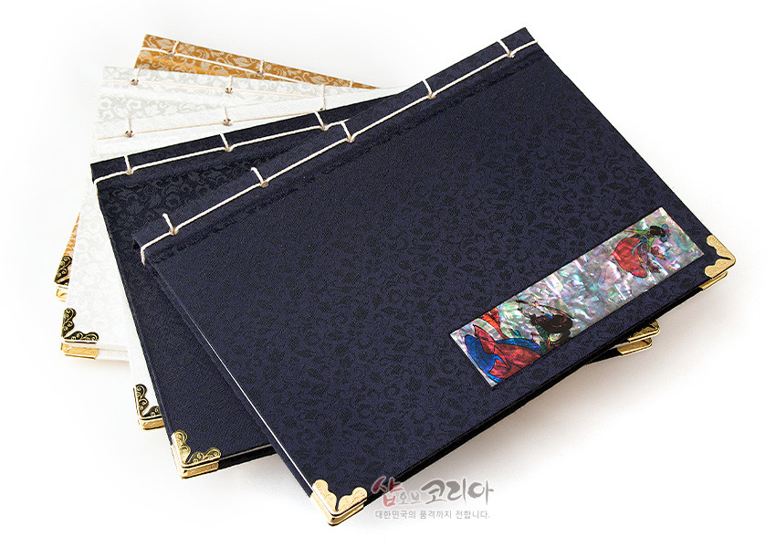 [텍스트: 샵오브코리아 대한민국의 품격까지 전합니다.] 네이비와 아이보리 비단 표지에 은은한 문양, 자개 상감 장식과 금속 모서리, 전통 끈 제본이 어우러진 오침노트 구성