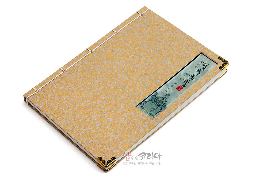 [텍스트: 훈민정음 세종대왕] 황금색 비단 바탕에 꽃문양 직조, 자개로 세종대왕 초상과 훈민정음 글귀 장식, 흰 실의 전통 오침안정법 제본과 모서리 금속 장식 노트 모습