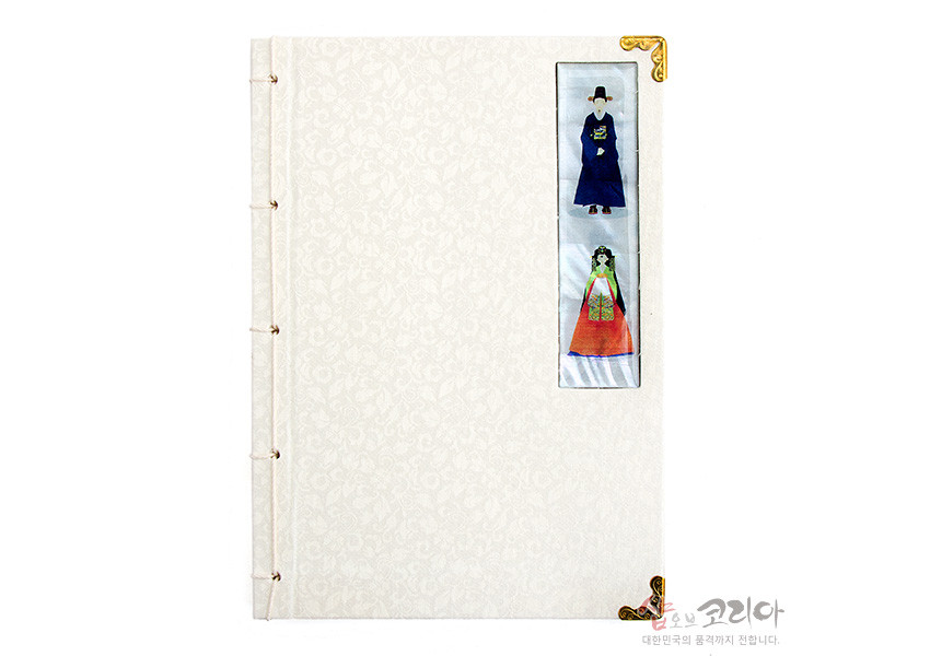 [텍스트: 샵오브코리아 대한민국의 품격까지 전합니다.] 아이보리 비단 위 음각 꽃무늬와 자개 신랑신부 장식, 황동 모서리 장식, 전통 오침 제본 노트 디자인