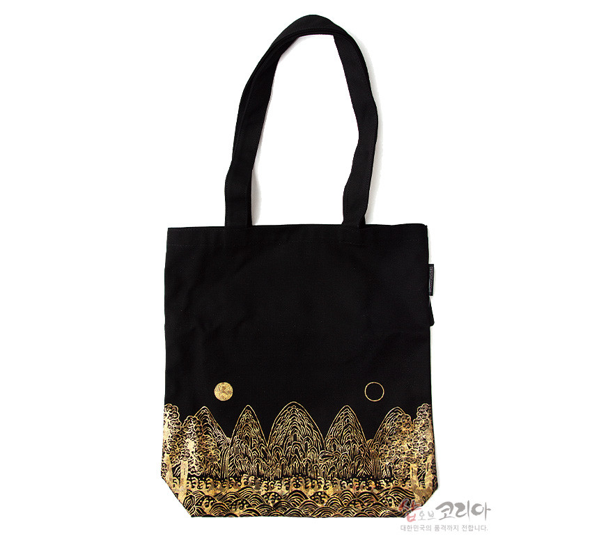 [텍스트: 샵오브코리아 대한민국의 문화를 전합니다.] 검은 천 소재에 금색 일월오봉도 산과 파도, 해와 달 문양이 실크스크린으로 표현된 에코백 디자인