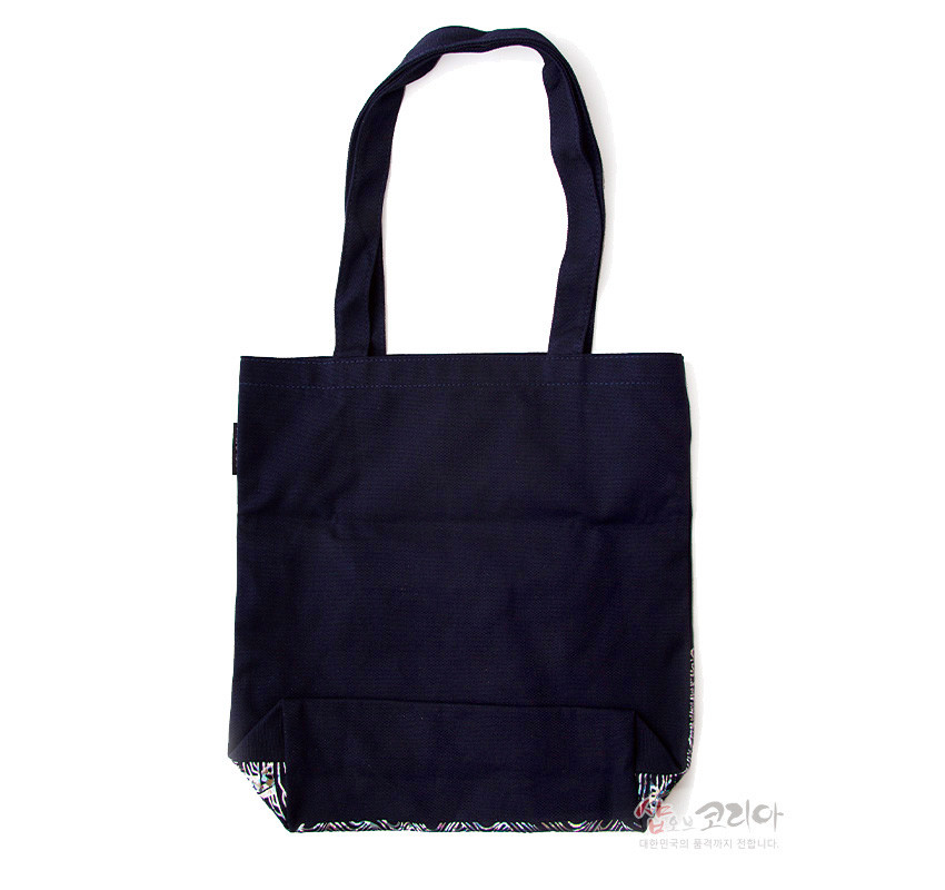 [텍스트: 샵오브코리아 대한민국의 품격까지 전합니다.] 짙은 남색 면 소재로 제작된 심플한 기본형 에코백, 하단에 은은한 전통 문양 포인트 처리된 디자인