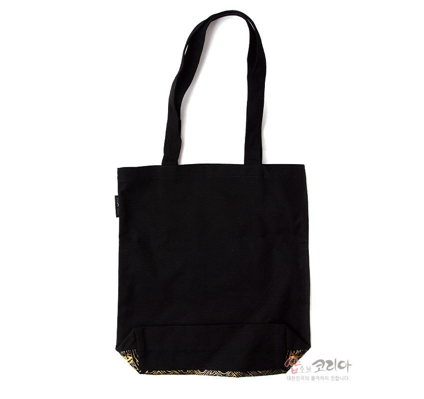 [텍스트: 샵오브코리아 대한민국의 품격까지 전합니다.] 검은 천 소재의 긴 손잡이 에코백, 하단에 금색 전통 기하학 문양 포인트로 장식된 디자인
