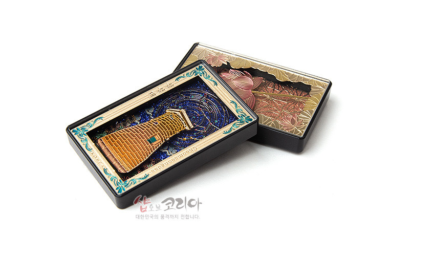 [텍스트: GYEONGJU CHEOMSEONGDAE] 금속 재질 입체 첨성대 조형과 짙은 남색 밤하늘, 청록색과 금색 장식 테두리가 어우러진 직사각형 마그넷형 장식품 모습