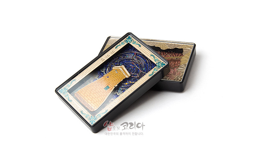 [텍스트: shop of korea] 금속 재질 입체 첨성대 조형과 청색 나선형 밤하늘, 금색 테두리와 청록색 장식 문양이 어우러진 직사각형 마그넷 디자인 이미지