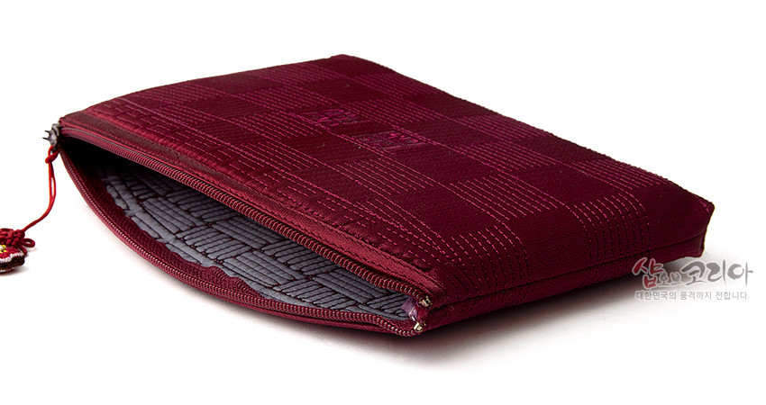 [텍스트: 샵오브코리아 대한민국의 품격까지 전합니다.] 적갈색 비단 누비 처리와 격자 자수 문양, 중앙 전통 문자 문양이 더해진 지퍼형 파우치와 회색 누빔 안감 디자인