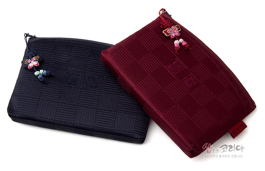 [텍스트: 샵오브코리아] 적갈색 비단 누비 원단에 격자 문양과 음각 전통 문자무늬를 넣고 나비 매듭 장식 지퍼 손잡이를 더한 직사각형 파우치 이미지