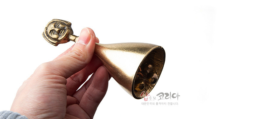 [텍스트: 샵오브코리아 대한민국의 품격까지 전합니다.] 황동 재질로 제작된 소형 종, 손잡이 부분에 입체적으로 표현된 부네탈 문양이 장식된 전통 공예품 이미지 설명