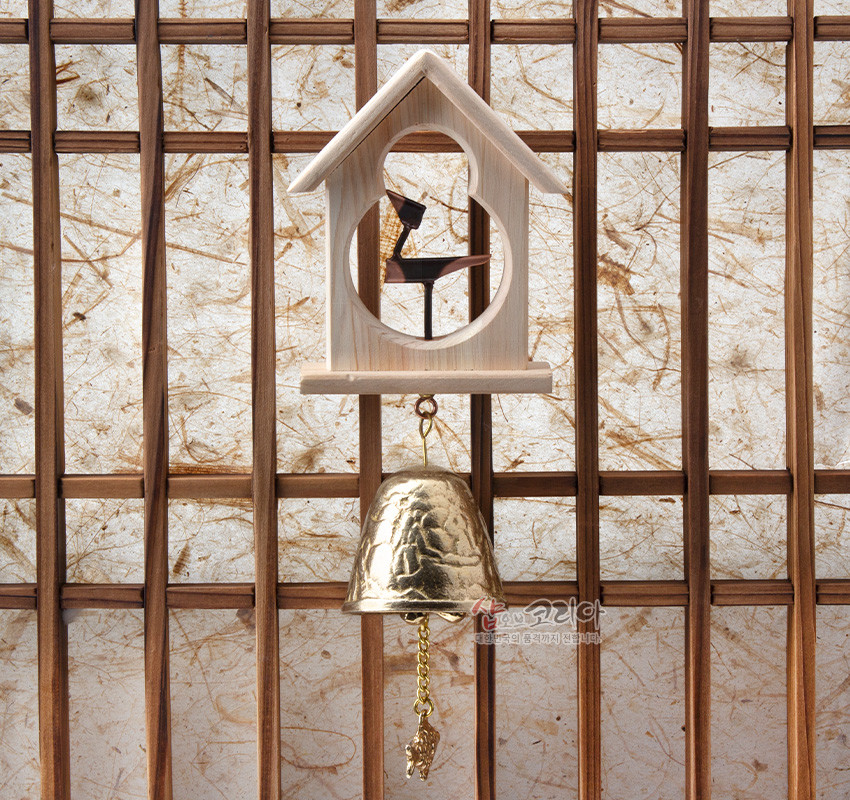 [텍스트: 샵오브코리아] 밝은 원목 집 모양 틀에 검은 솟대 장식 배치, 아래로 조각무늬 황동 종과 황동 물고기 추 장식이 달린 전통 문종 인테리어 소품