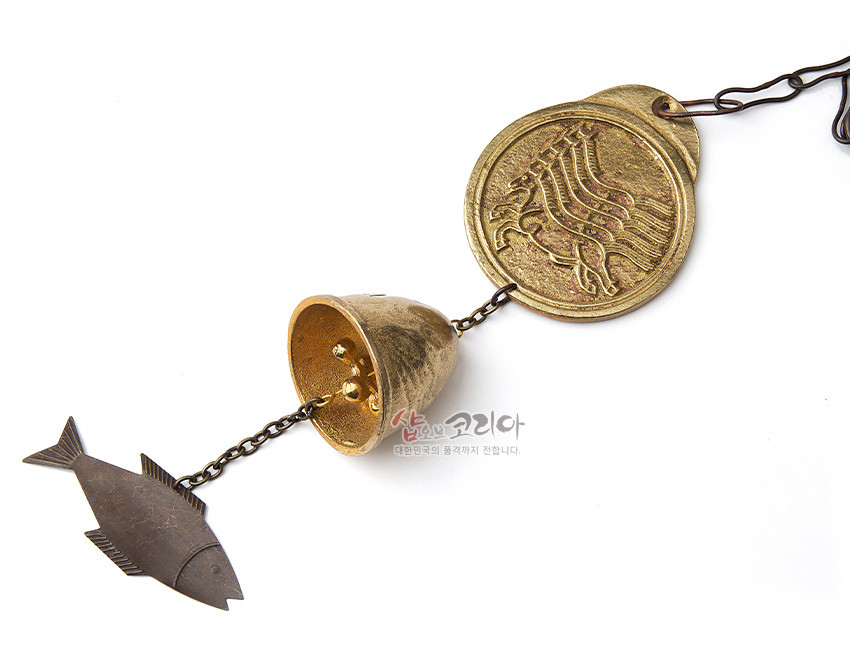 [텍스트: 샵오브코리아 대한민국의 품격까지 전합니다.] 황동 재질 원형 마패 문양 판과 금속 종, 사슬에 연결된 물고기 모양 추 장식이 조화를 이룬 전통 풍경종 이미지