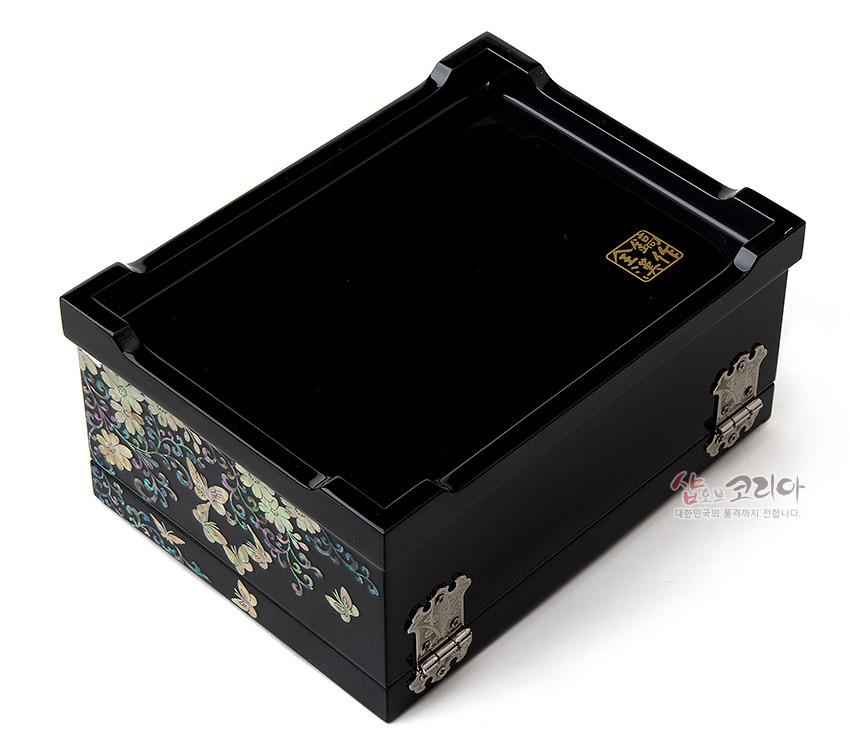 [텍스트: 샵오브코리아 대한민국의 품격까지 전합니다.] 흑색 옻칠 위 자개 상감으로 꽃과 나비 문양을 장식하고 금속 경첩을 더한 직사각 나전 보석함 디자인