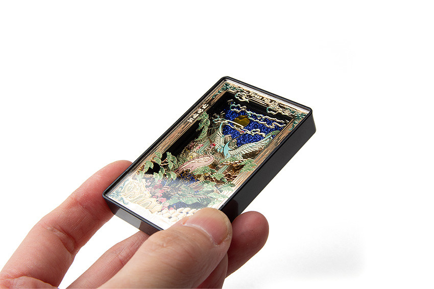 금속 재질 직사각형 마그넷 위에 입체 양각 기법으로 학, 소나무, 구름과 해를 다채로운 색상으로 표현한 십장생도 문양 장식 이미지 설명