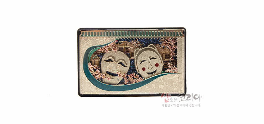 [텍스트: 안동 하회 마을] 금속 재질 위에 부조 기법으로 표현된 하회탈과 하회마을 전경, 분홍 꽃무늬와 녹색 곡선 장식이 어우러진 직사각형 입체 마그넷 디자인