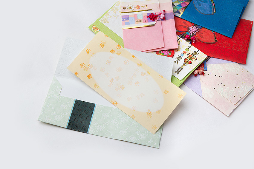 파스텔 톤 한지 재질 봉투와 카드 위에 전통문양 양각 처리, 오방색 조각보 패턴과 꽃 매듭 장식이 어우러진 축하용 전통 봉투 세트 이미지 설명