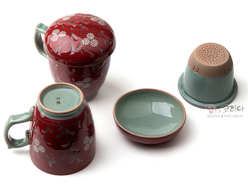 [텍스트: 샵오브코리아 대한민국의 품격까지 전합니다.] 붉은 유약 바탕 위 국화와 넝쿨 문양이 시문된 도자 머그다기잔 세트, 연녹색 내면과 손잡이, 거친 토 분체 거름망이 조화를 이룬 구성